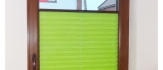 Zielona plisa okienna w brązowej ramie